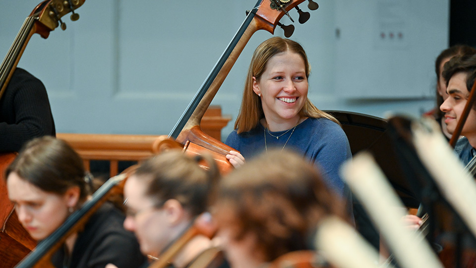 A double bass player smiling in an orchestral rehearsal